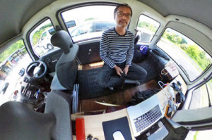 独立型ソーラーの実践者を訪ねて全国取材の旅に出る新井さんと軽自動車の車内(新井由己さん提供)