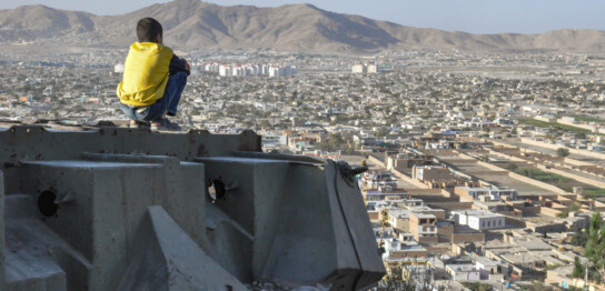アフガニスタン・カブールの市で、破壊されたタンクに座る少年（2012年撮影）（画像はイメージ）